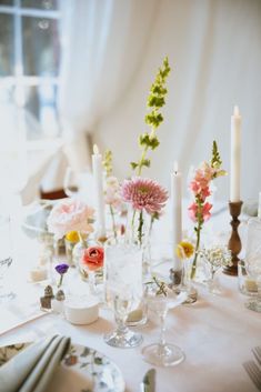 the table is set with flowers, candles and dishes for an elegant dinnereone