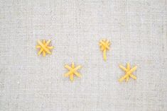 three small yellow crosses sitting on top of a piece of cloth next to each other