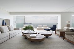 a living room filled with lots of furniture and a large window overlooking the ocean in front of it