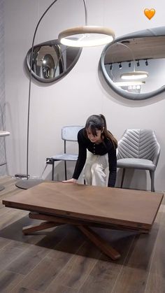 a woman standing in front of a wooden table