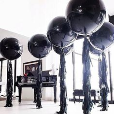 black balloons and tassels are arranged in the middle of a room with piano