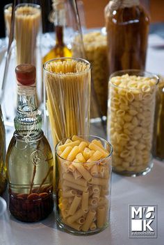 several bottles and glasses filled with pasta on a table