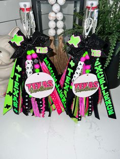 two black and green hair bows with the word texas on them sitting in front of a mirror