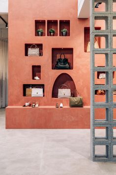 an orange wall with shelves and purses on it