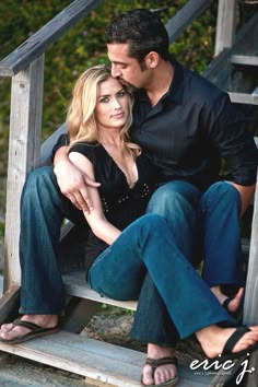 a man and woman are sitting on steps in front of some stairs with their arms around each other