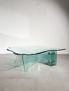 a glass table sitting on top of a floor next to a white wall in a room