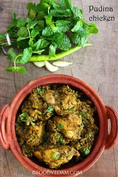 a bowl filled with chicken and greens next to some green vegetables on a wooden table