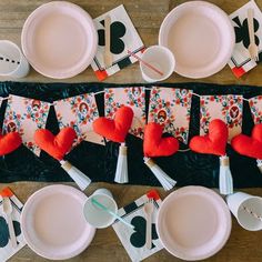 the table is set for valentine's day with paper hearts and napkins on it