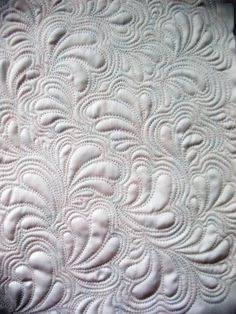 a close up view of an intricate white quilt