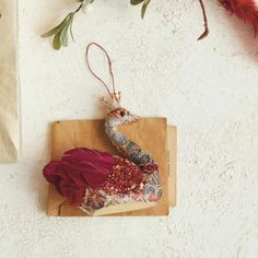 a bird ornament hanging on a piece of wood next to flowers and fabric