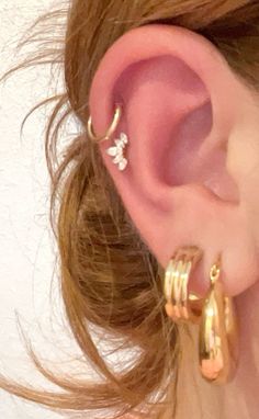 a close up of a person's ear with two gold hoops on it