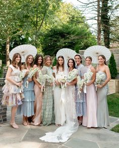 a group of women standing next to each other with umbrellas over their heads and holding bouquets