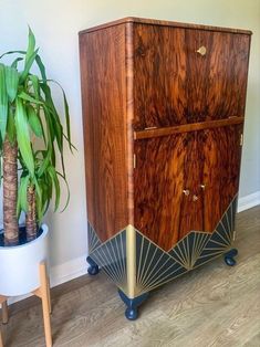 a wooden cabinet sitting next to a potted plant