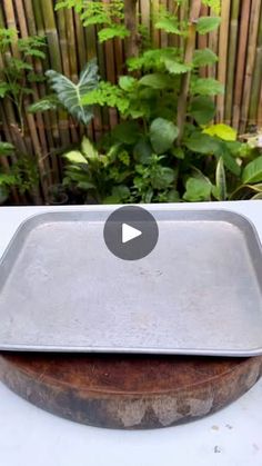 a metal tray sitting on top of a table next to a wooden board and plants