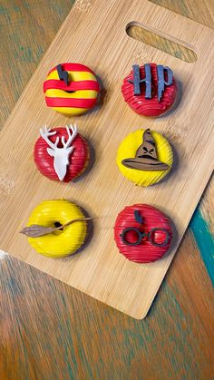 four decorated donuts sitting on top of a wooden cutting board