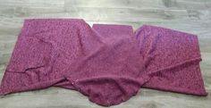 two pieces of purple fabric laying on top of a wooden floor