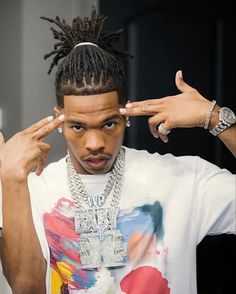 a young man with dreadlocks is holding his hands up to his forehead and looking at the camera