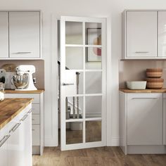 a kitchen with white cabinets and wooden counter tops, along with an open pantry door