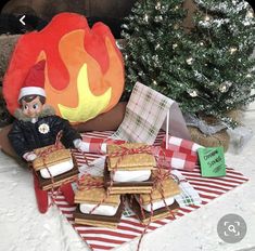 a table topped with cookies and marshmallows next to a christmas tree