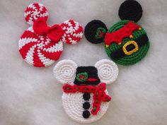 three crocheted mickey mouses are laying on a white surface with red and green decorations