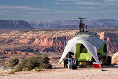 a tent set up in the desert with mountains in the background