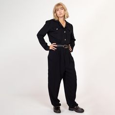 Vintage 80s black long sleeve jumpsuit with jeweled buttons down the bodice, a fitted waist with elastic at the back, and tapered legs. It has a zipper fly with two buttons at the waist, and decorative chest pockets. Shown modeled with a belt in the first two photos (not included with purchase).   Measurements and Condition: Fits like: Labeled size 13/14 tall (women's large tall) Fabric: Acetate/rayon - labeled dry clean only Brand: Avon Fashions, made in USA Condition: Excellent Length: 63" Chest: 41.5" Waist: 27" to 33" - stretches with elastic at back  Hips: 46" - taken at the bottom of the zipper opening Rise to waist: 15" Inseam: 32" Shoulders (seam to seam): 16" Sleeve: 24" Cuff: 8.5" Shown on a 5'7" model with measurements of 37"-30"-39.5", usually wears a size medium. See our FAQ f Black Long Sleeve Jumpsuit With Button Closure, Retro Workwear Jumpsuits And Rompers, Retro Style Workwear Overalls And Rompers, Retro Fitted Long Sleeve Jumpsuits And Rompers, Vintage Long Sleeve Jumpsuits And Rompers For Work, Vintage Long Sleeve Jumpsuit For Work, Vintage Long Sleeve Jumpsuits And Rompers For Fall, Retro Long Sleeve Jumpsuits And Rompers For Fall, Retro Long Sleeve Jumpsuit For Fall