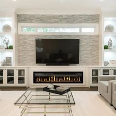 a living room with a fireplace, couches and a flat screen tv on the wall