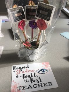 there is a vase with flowers in it on the table next to a teacher's note