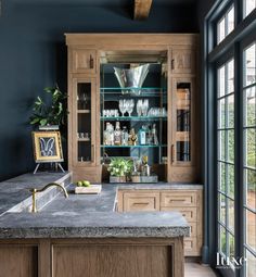 a kitchen with blue walls and wooden cabinets in the center is a marble counter top