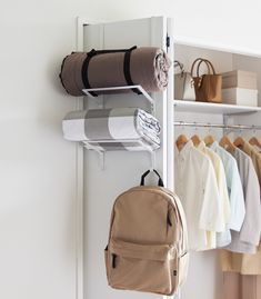 there is a backpack hanging on the wall next to a rack with folded towels and sweaters