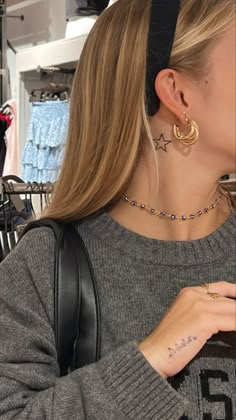 a woman is looking at her cell phone while wearing ear rings and a black headband