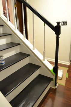 the stairs are painted black and white with green tape on them, along with a can of paint