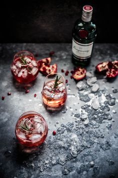 two glasses filled with ice and garnish next to a bottle