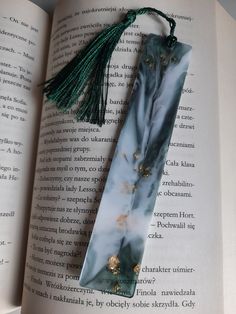 the bookmark is laying on top of an open book with beads and tassels