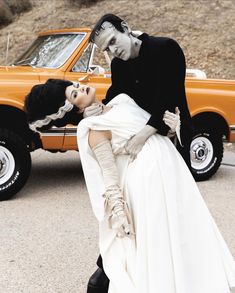 a couple dressed up as skeletons kissing in front of a car