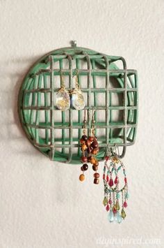 a green rack with earrings hanging from it's sides on the wall next to a white wall