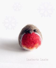 a small red and white ball with snowflakes on it's sides, sitting in front of a white background