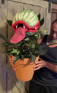 a man holding a potted plant with a monster face on it