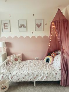 a bedroom with a pink canopy bed and white furniture in the corner is lit by fairy lights