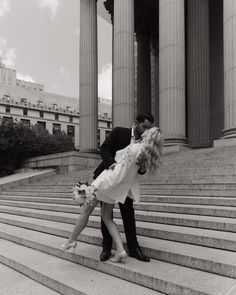 a man and woman kissing on the steps of an old building in black and white