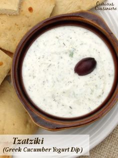 a bowl of greek cucumber yogurt dip with pita chips on the side