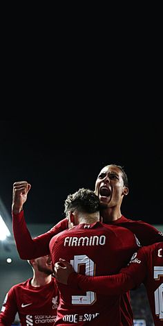 two soccer players are hugging each other in the middle of a group celebrating their team's goal