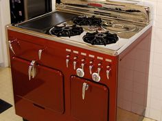 a red stove top oven sitting inside of a kitchen