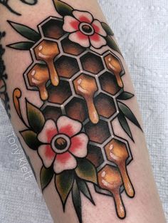 a tattoo with honeycombs and flowers on the arm, done by an artist