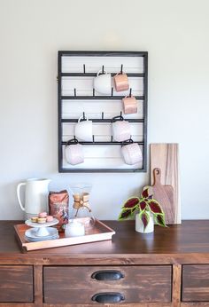 a wooden table topped with lots of cups and saucers next to a wall mounted shelf