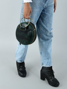 Introducing our latest fashion marvel -Rosie Sling Circle Bag. This unique and stylish accessory is designed to make a bold statement wherever you go. Crafted from high-quality dark green buffalo leather, it exudes an air of sophistication and elegance, while its circular shape adds a touch of whimsy to your ensemble. The trendy and practical sling design allows you to carry your essentials comfortably and in style, leaving your hands free for whatever the day holds. Whether you're heading to a Trendy Round Case Shoulder Bag For Everyday, Elegant Shoulder Bag With Chain Strap And Round Handle, Chic Shoulder Bag With Chain Strap And Round Handle, Modern Bags With Round Handle And Leather Lining, Green Shoulder Bag With Detachable Strap And Round Handle, Leather Shoulder Bag With Detachable Handle And Round Case, Leather Shoulder Bag With Detachable Handle In Round Shape, Green Leather Shoulder Bag With Round Handle, Leather Bucket Bag With Round Handle For On-the-go