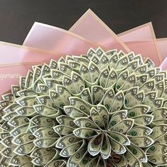 a bunch of money sitting on top of each other in front of pink envelopes