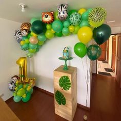 the balloon arch is decorated with jungle animals and green, yellow, and blue balloons