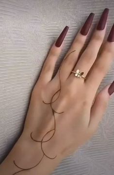 a woman's hand with a ring on it and her nails painted maroon,