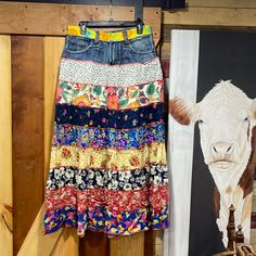 a cow's head hangs next to a colorful skirt hanging on a wooden wall